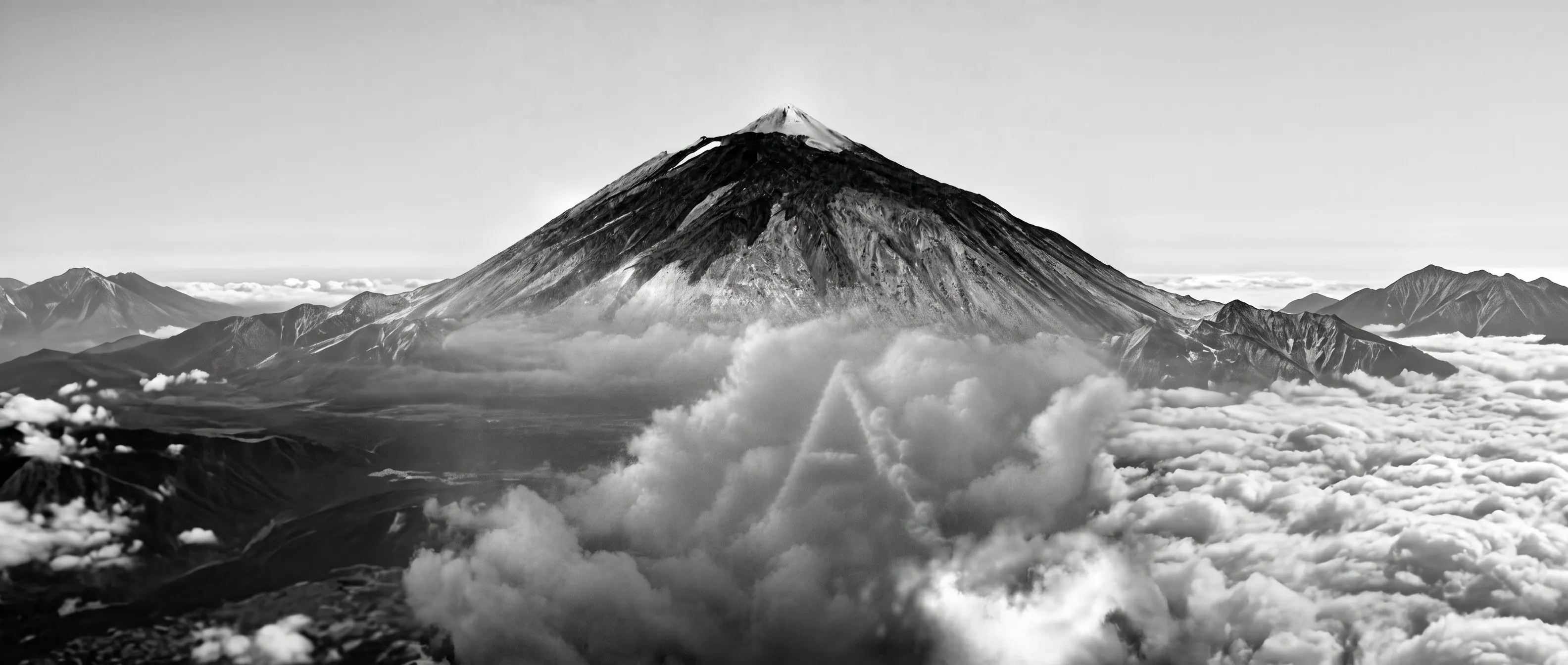 A snow-dusted mountain peak rising above a bank of cloud.